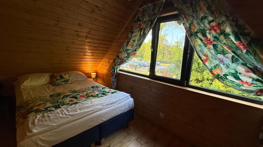 a small bedroom with a bed and two windows at Osada Międzywodzie in Międzywodzie