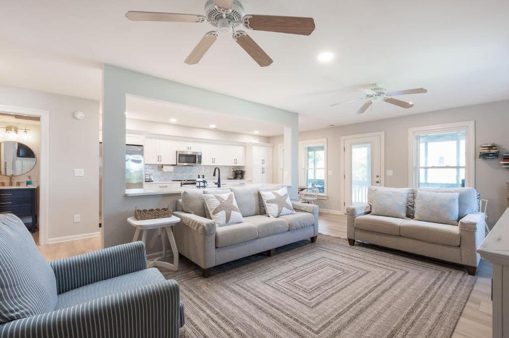 Jay CrestにあるNewly Listing Renovated bungalow steps from waterのリビングルーム(ソファ2台、天井ファン付)