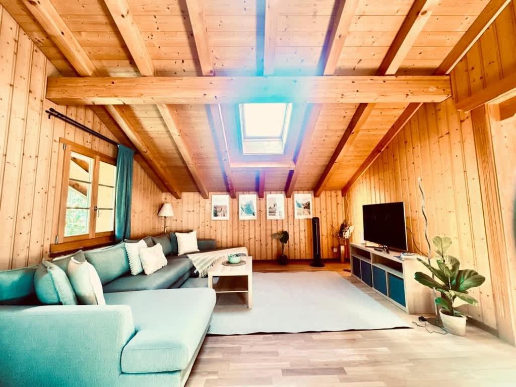 a living room with a blue couch and a tv at Chalet with Scenic Valley & Mountain Views in Lütschental