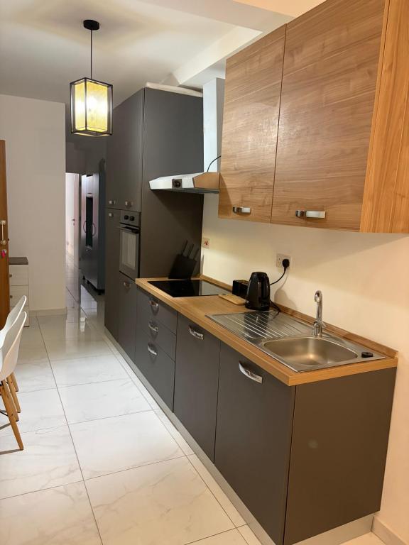 a kitchen with gray cabinets and a sink at Tedds Cosy 2 bedroom Apartment in Tal-Pietà
