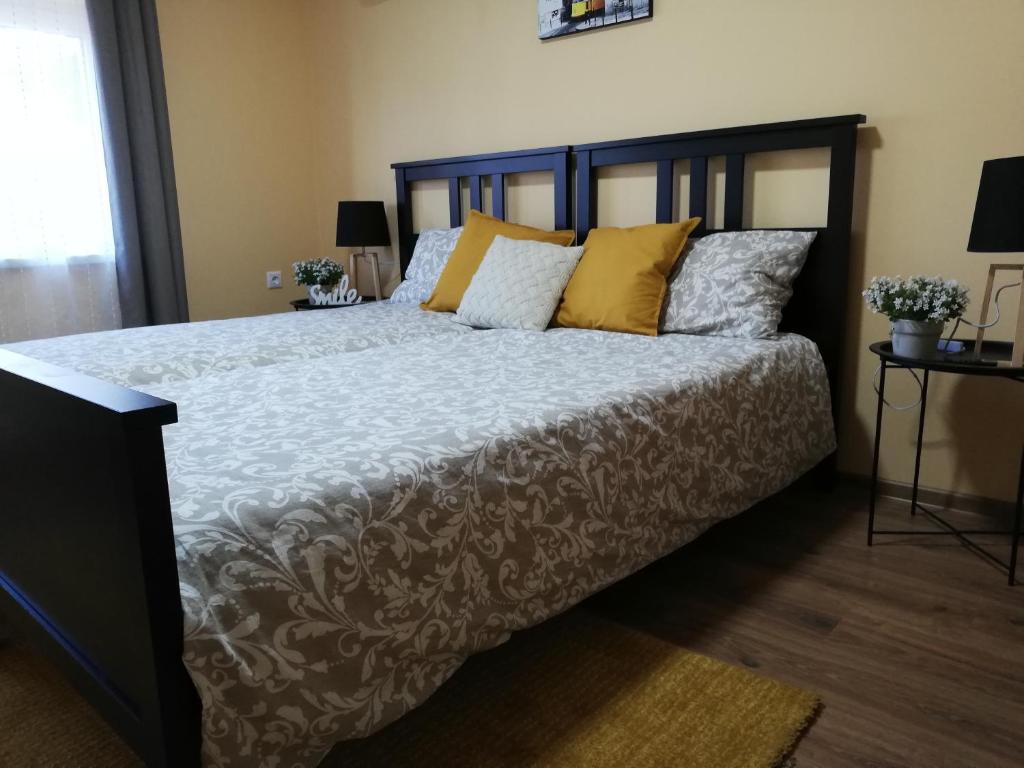 a bedroom with a large bed with yellow pillows at Téged Vártunk Vendégház in Bakonyoszlop