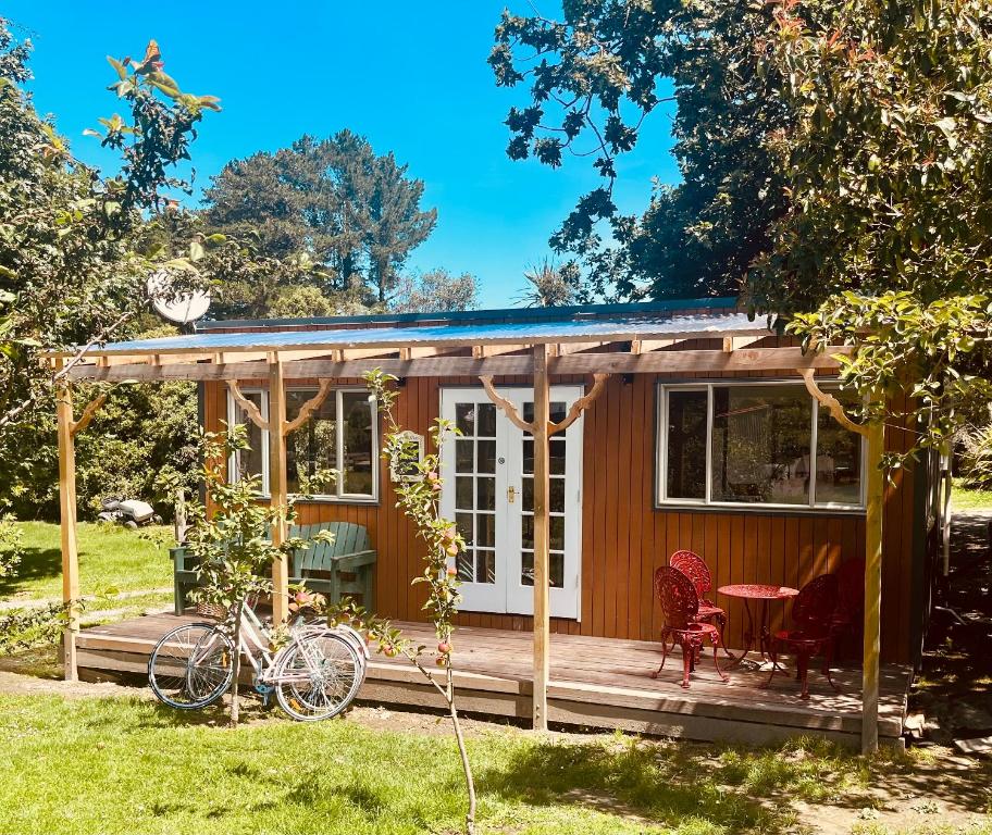 une petite maison avec une véranda, une table et des chaises dans l'établissement Wattle Creek Cottage with Breakfast Basket, à Amberley