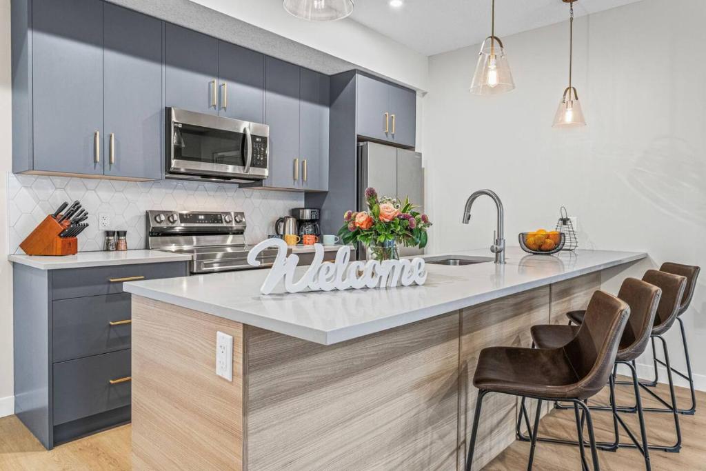 una cocina con armarios azules y una isla de cocina con sillas en Spacious 3BR Haven in Scenic Canmore, en Canmore