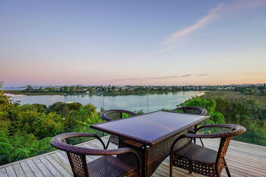 einen Tisch und Stühle auf einer Terrasse mit Flussblick in der Unterkunft Tranquil West Haven with Water and Skyline Views in Auckland