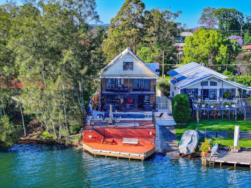 a boat is docked at a house on the water at Dora Creek Escape with Pool and Spa in Dora Creek