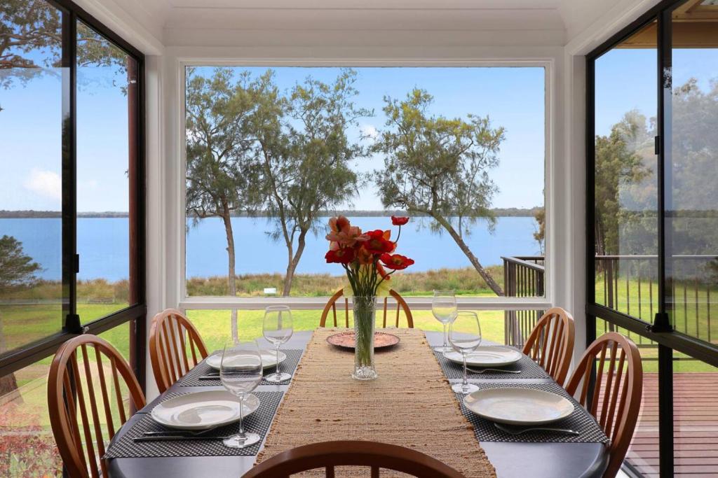 a dining table with a vase of flowers on a porch at Lakeside Getaway Halekulani in Budgewoi