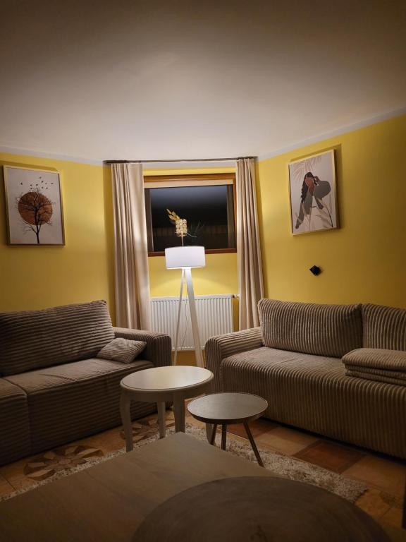 een woonkamer met twee banken en een tafel bij Apartament Biała Flaga Cozy apartment by the lake in Charzykowy