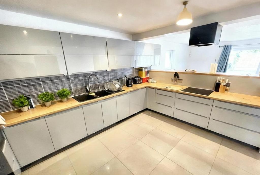 a large kitchen with white cabinets and a large window at NexStay Bournemouth Retreat 5 Bed Luxe Bungalow in Bournemouth
