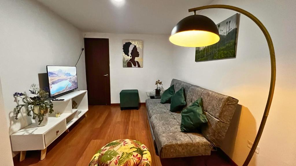 a living room with a couch and a flat screen tv at Dúplex familiar cerca al Cable y Milán con patio in Manizales