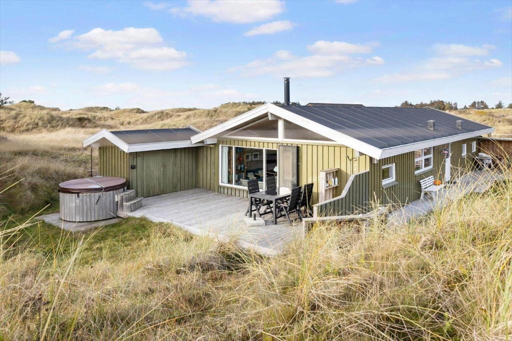 a green house with a deck in a field at TV1694-Bindslev-Musvagevej-8 in Tversted