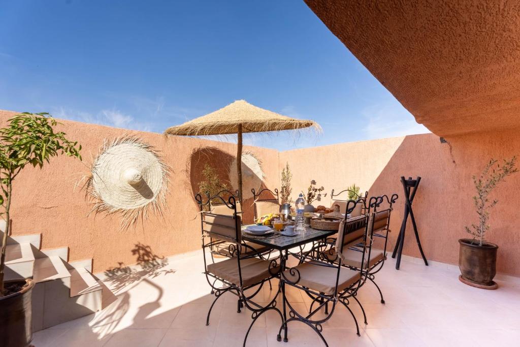 a table with chairs and an umbrella on a patio at Lyxig oas i Medina och fantastisk terrass in Marrakech