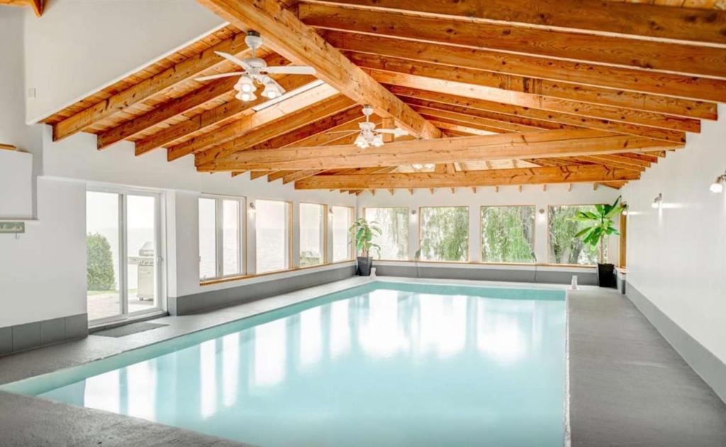 a large swimming pool with a wooden ceiling and windows at Heated Indoor Pool - Maison au Bord du Lac in Rigaud