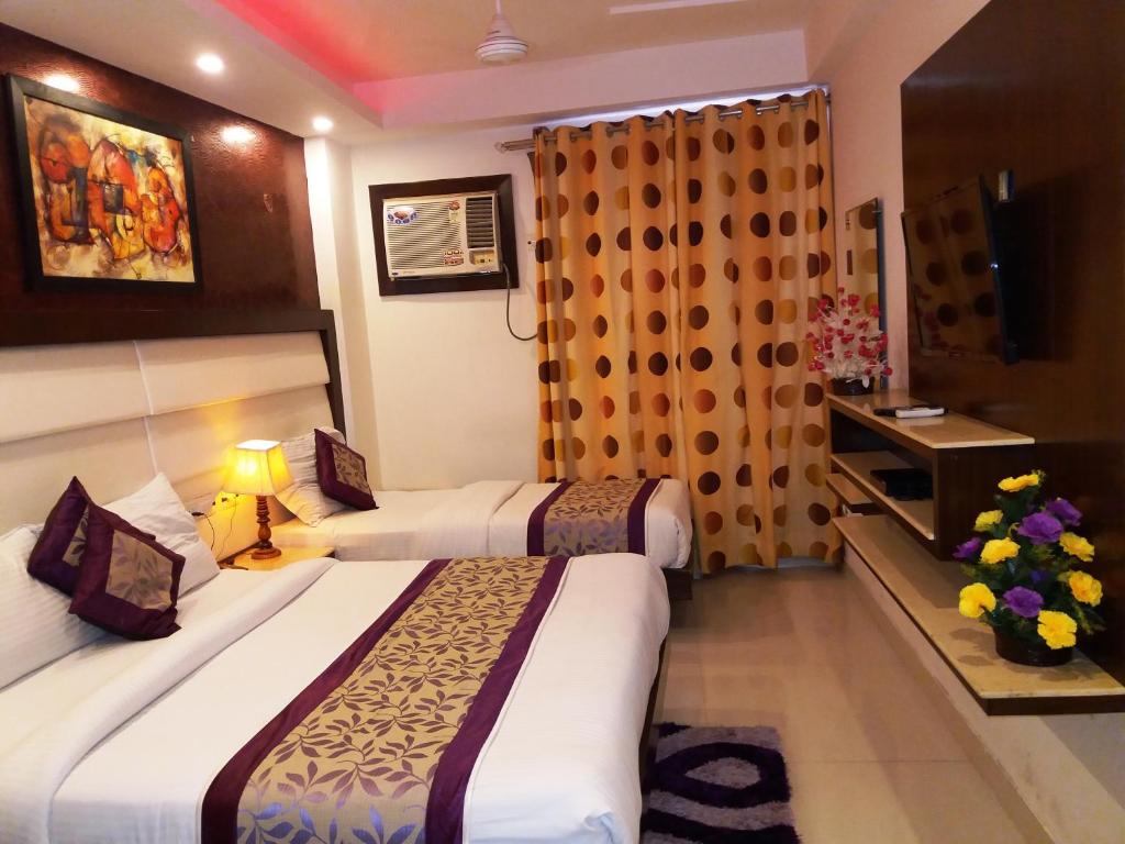 a hotel room with two beds and a television at Hotel Station View in New Delhi