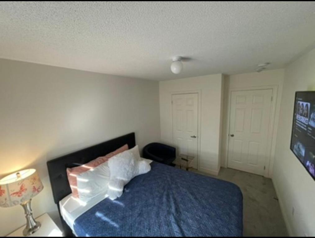 a bedroom with a bed with a blue blanket and white pillows at Budget Friendly Home in Oshawa