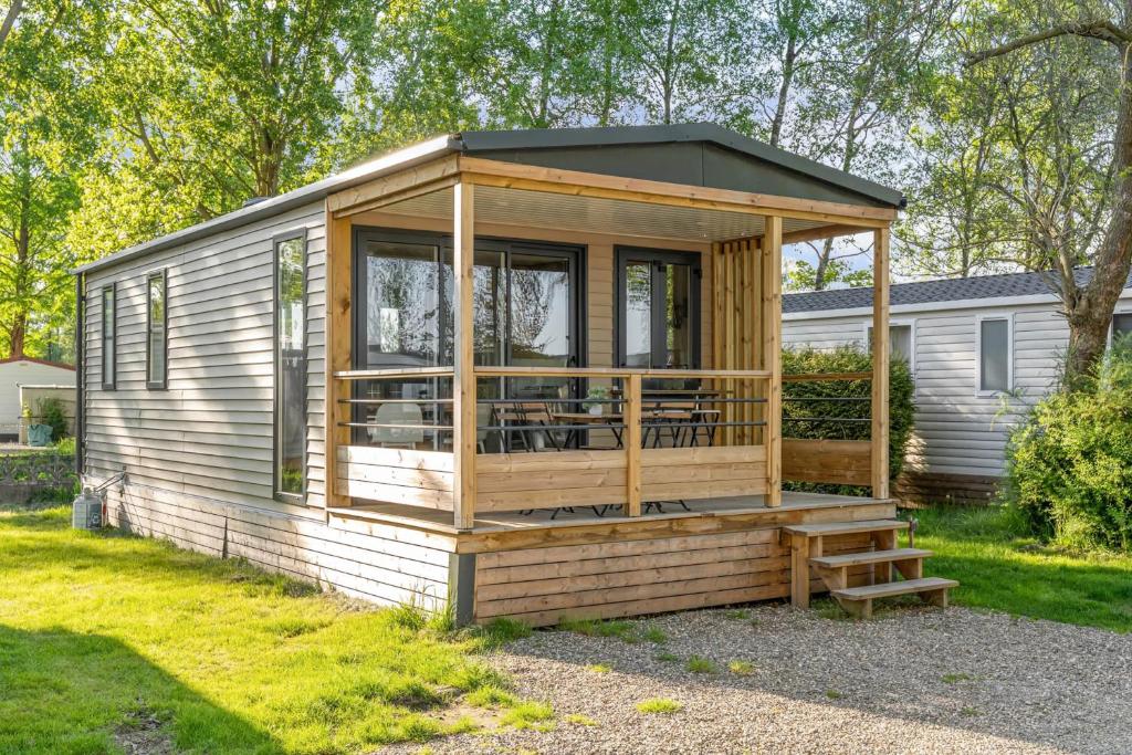 a wooden cabin with a porch and a deck at Camping Papillon Kinrooi - 78 in Kinrooi