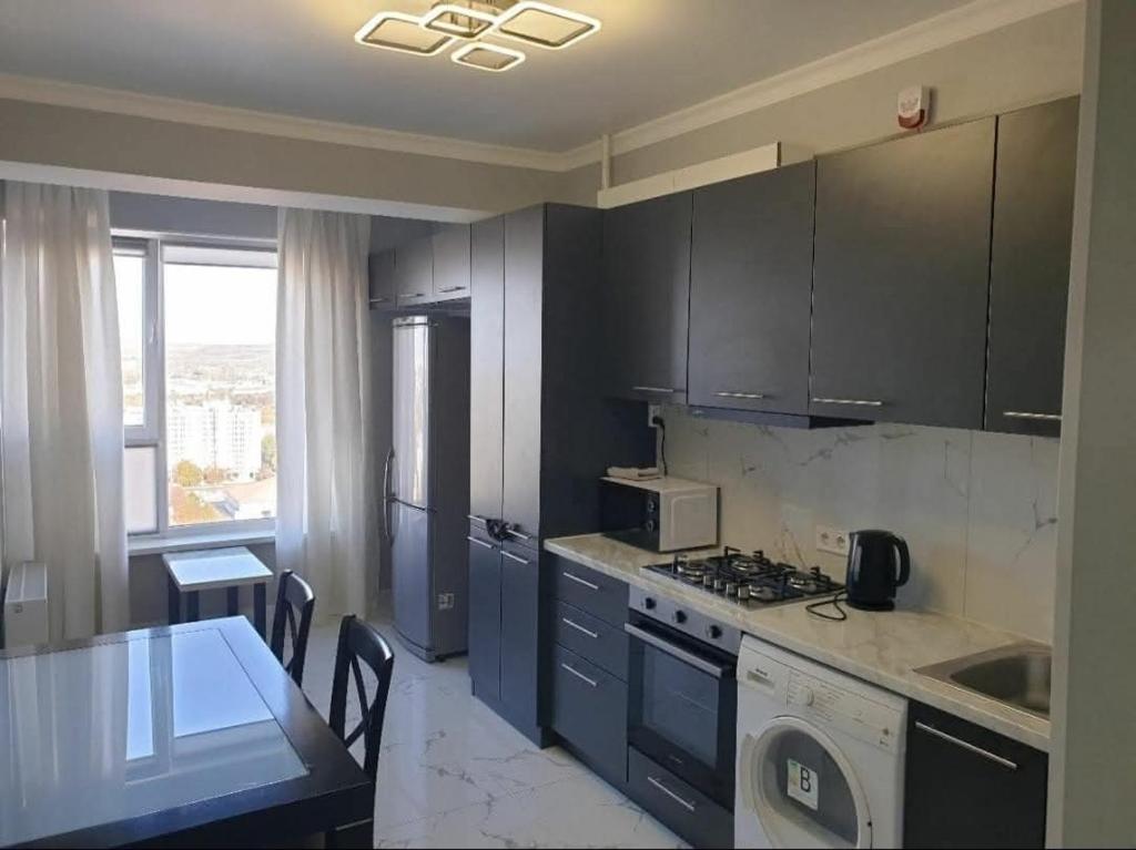 a kitchen with black cabinets and a table and a microwave at Botanica Aeroport in Chişinău