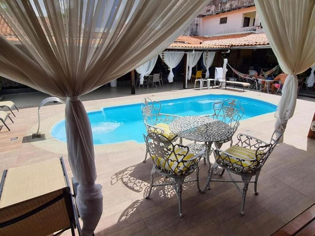 a table and chairs next to a swimming pool at Itaparica - Praia de Ponta de Areia in Itaparica Town