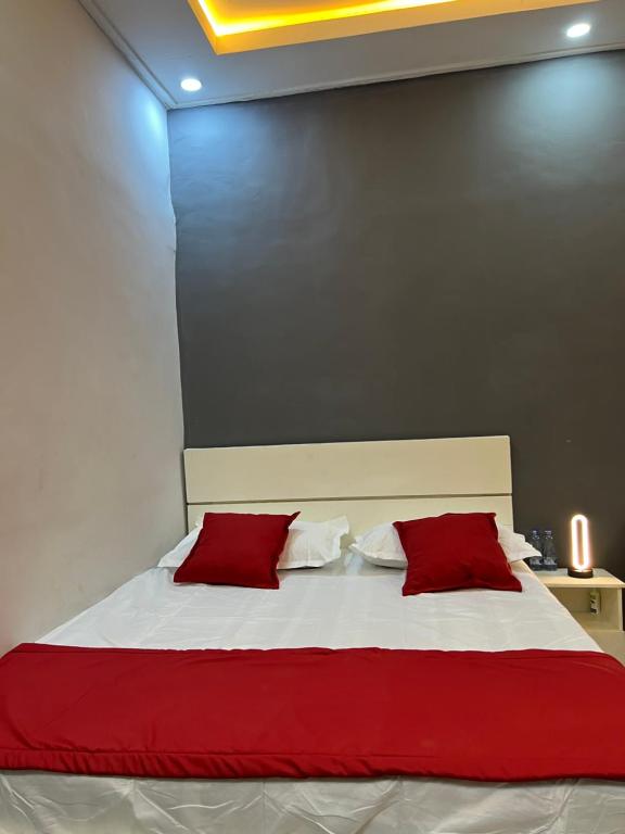 een slaapkamer met een groot bed met rode kussens bij Tataicha Stydio 1 in Ndjamena