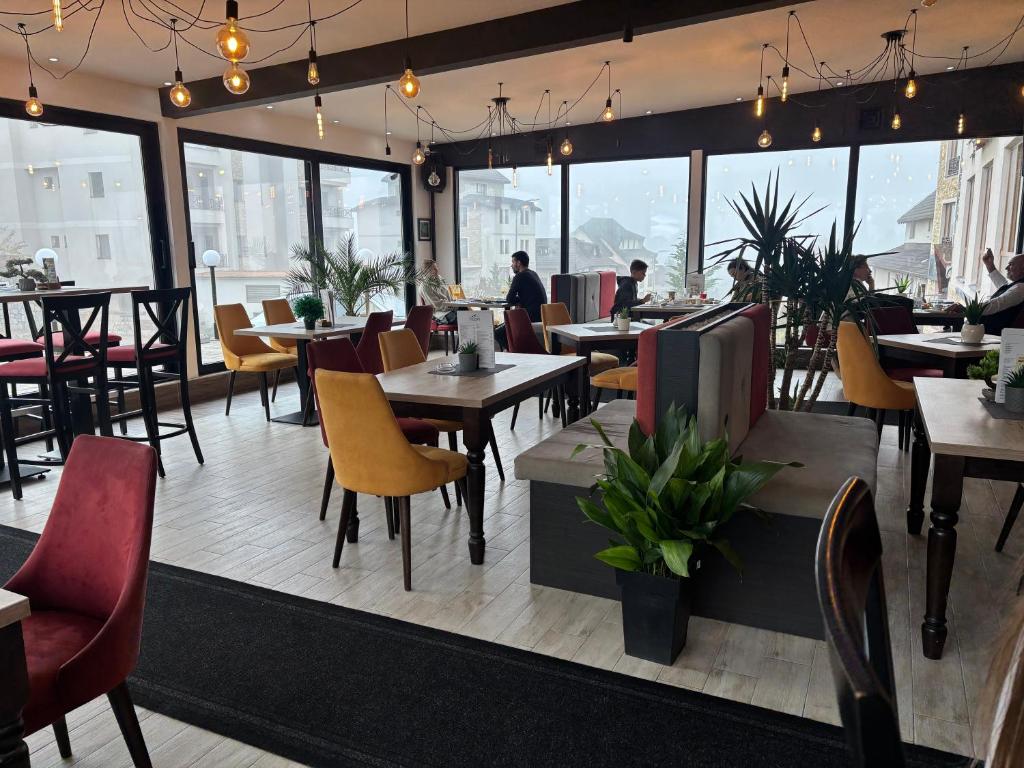 a restaurant with tables and chairs and windows at Amprtman PETKOVIĆ NLux 110 Milmari resort in Kopaonik