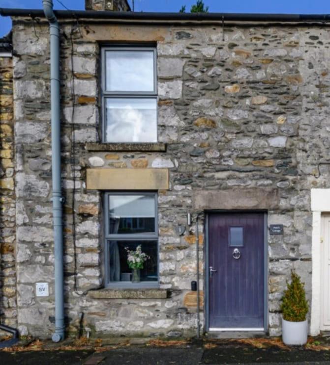 a stone house with a purple door and a window at 1, Bank End Cottages in Ingleton