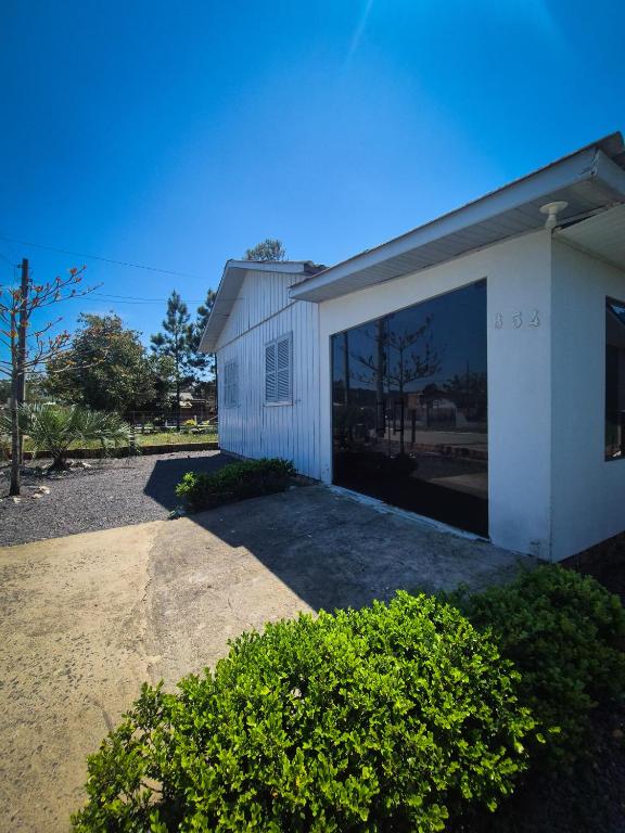 - un bâtiment blanc avec une grande porte en verre dans l'établissement Casa de temporada em Balneário Gaivota- Praia Onda Azul, à Balneário Gaivotas
