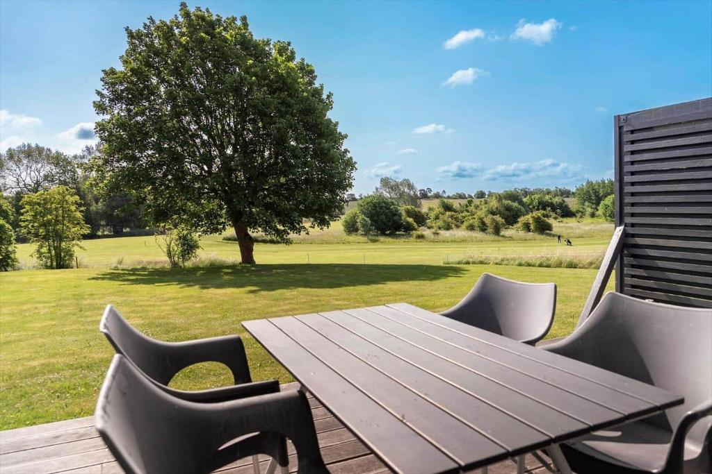 a wooden table and chairs on a deck with a field at 20424-Samso-Besser-Kirkevej-4-C in Langemark