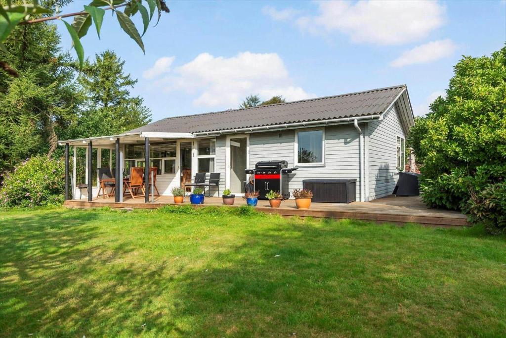 a white house with a porch and a yard at 30732-Odder-Skovgardsparken-32 in Amstrup