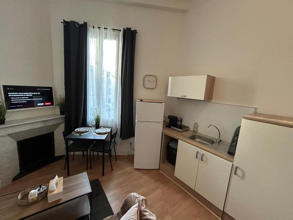 Una pequeña cocina con nevera y mesa. en Luberno studio lumineux parking inclus, en Cavaillon