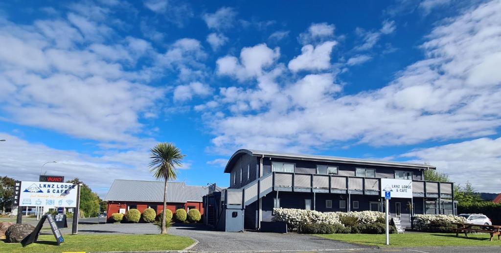 a black building with a palm tree in front of it at LKNZ Lodge & Cafe in Ohakune
