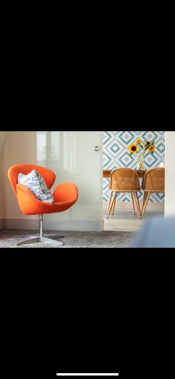 an orange chair sitting in a room with a table at 3 Bed Stylish Beachfront Retreat in Roche