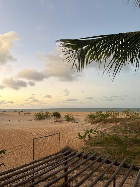 a view of a beach with a fence and the ocean at Chalé vista mar in São Miguel do Gostoso