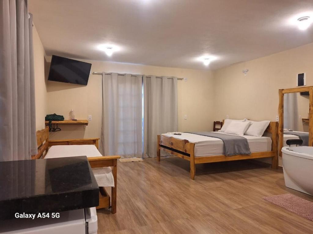 a bedroom with a bed and a tub and a television at Chalé Aconchego in Camanducaia