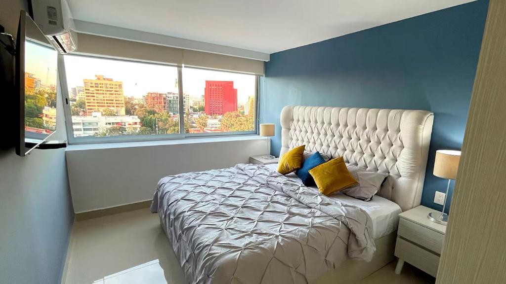 een slaapkamer met een groot bed met een groot raam bij 06 Loft Espectacular - Aire Acondicionado, Consulado in Guadalajara