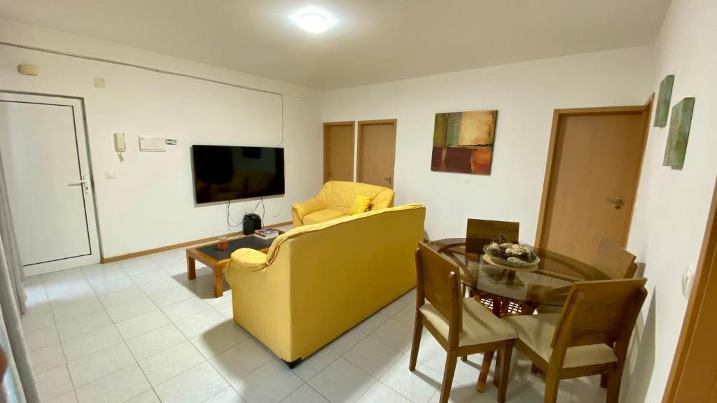 a living room with a yellow couch and a table at Airport Residence - Vila Acácia I in Praia