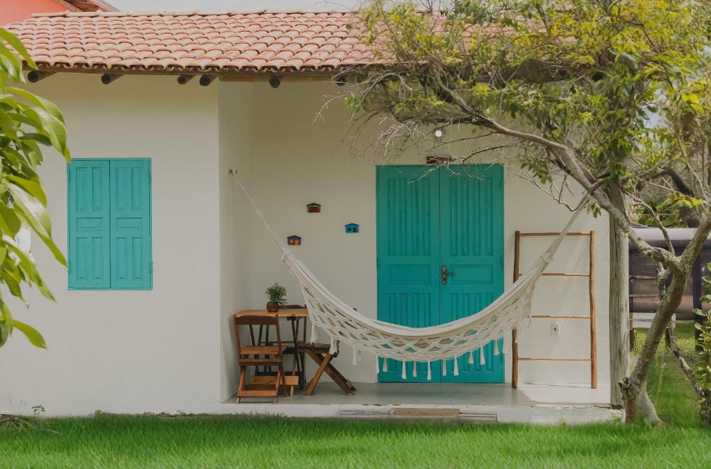 a hammock hanging from the side of a house with blue doors at Pousada Serena Chalés in Caraíva