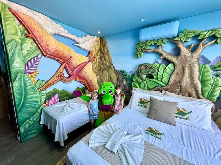 a bedroom with a dinosaur wall mural at Hotel Recanto dos Dinossauros in Penha