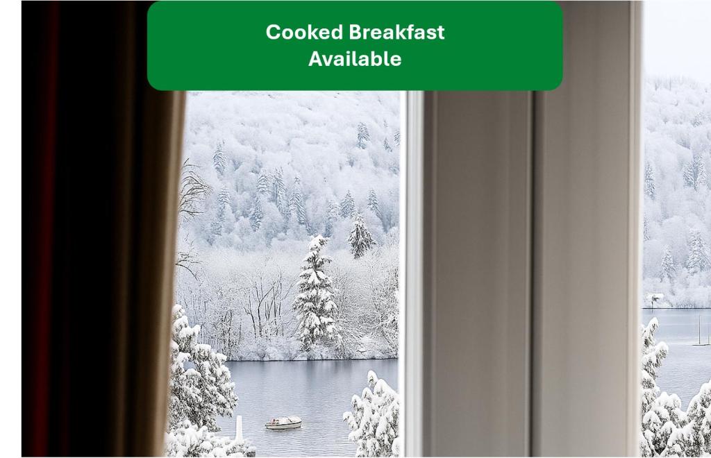 een raam met een besneeuwd uitzicht op een meer bij Bowness Bay Suites in Bowness-on-Windermere