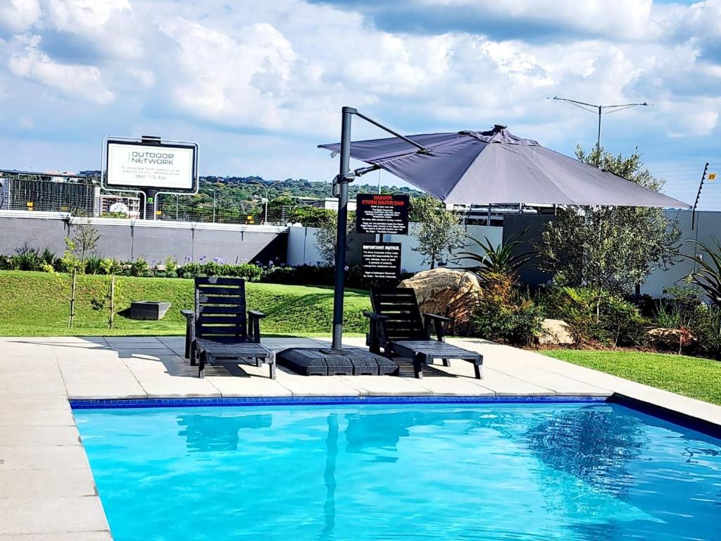a swimming pool with two chairs and an umbrella at Deplatinum Luxury Apartment-A Home away with love in Sandton