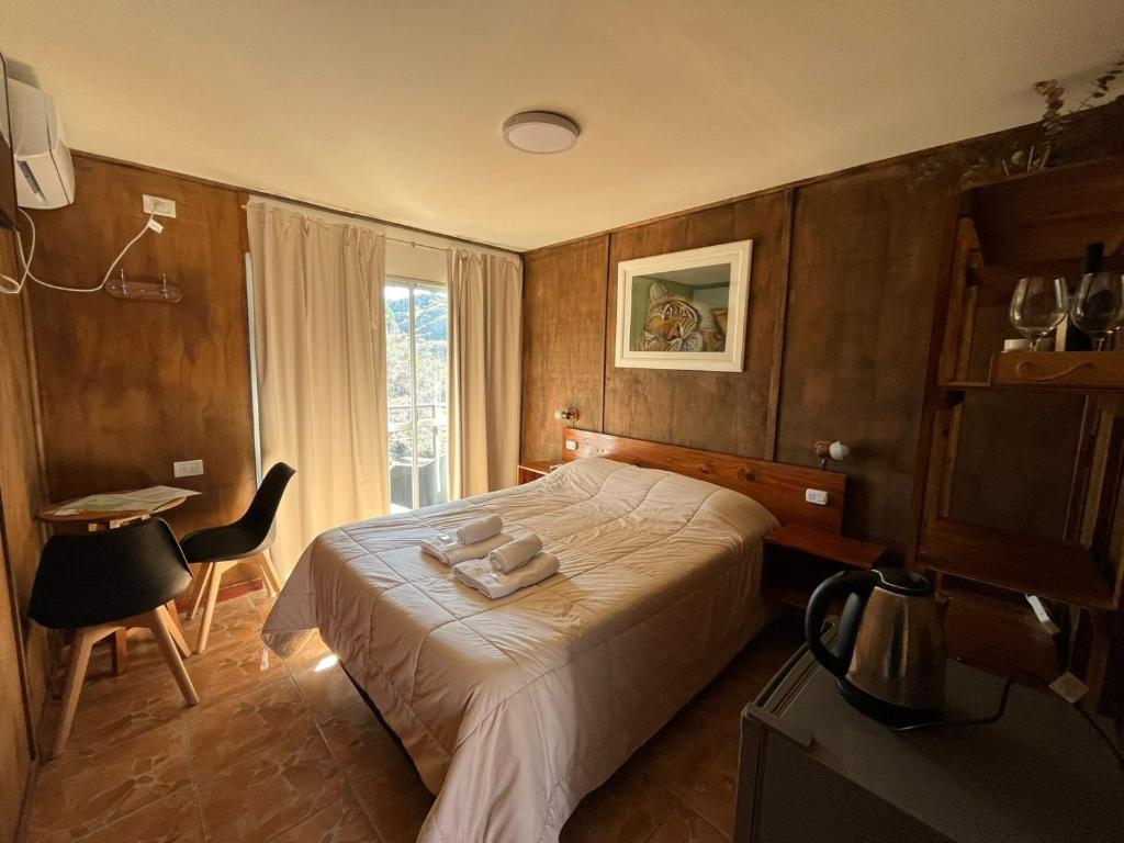 een slaapkamer met een bed, een tafel en een raam bij Village in La Cumbrecita