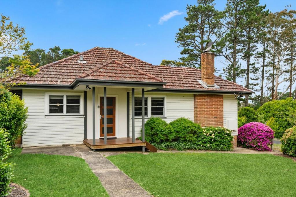 a small white house with a grass yard at Balgownie Cottage in Blackheath