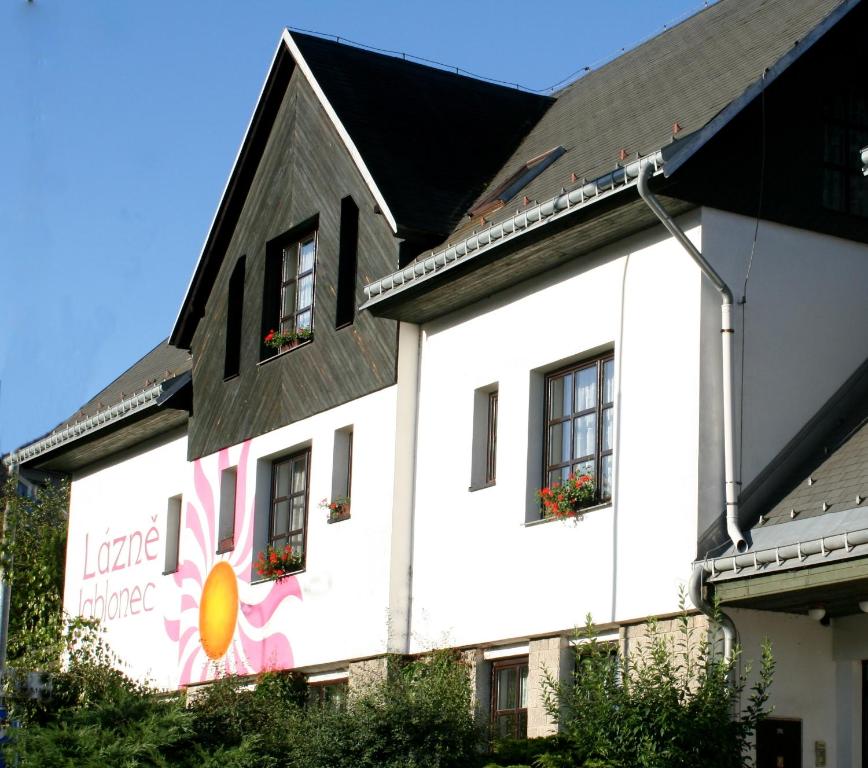 un edificio blanco con flores a un lado en Wellness Penzion Lázně Jablonec en Jablonec nad Nisou