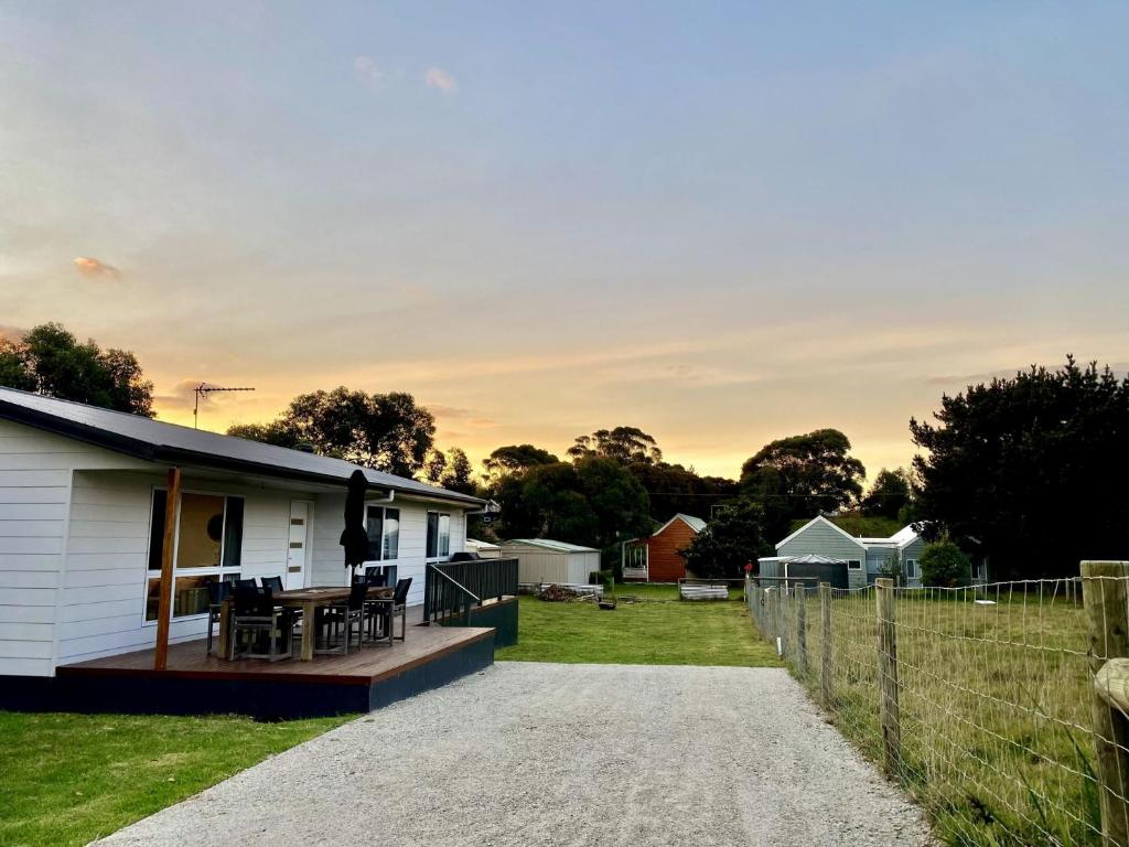 a white house with a porch and a fence at Bella's Beach House in Venus Bay