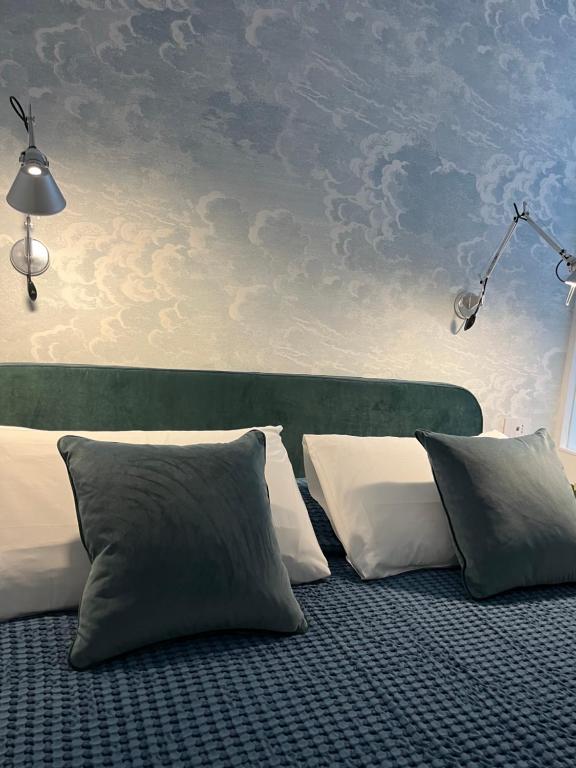 ポルトヴェーネレにあるAbout Italy Holiday Rooms and Apartmentsの白い枕が置かれたベッドと雲が描かれた壁