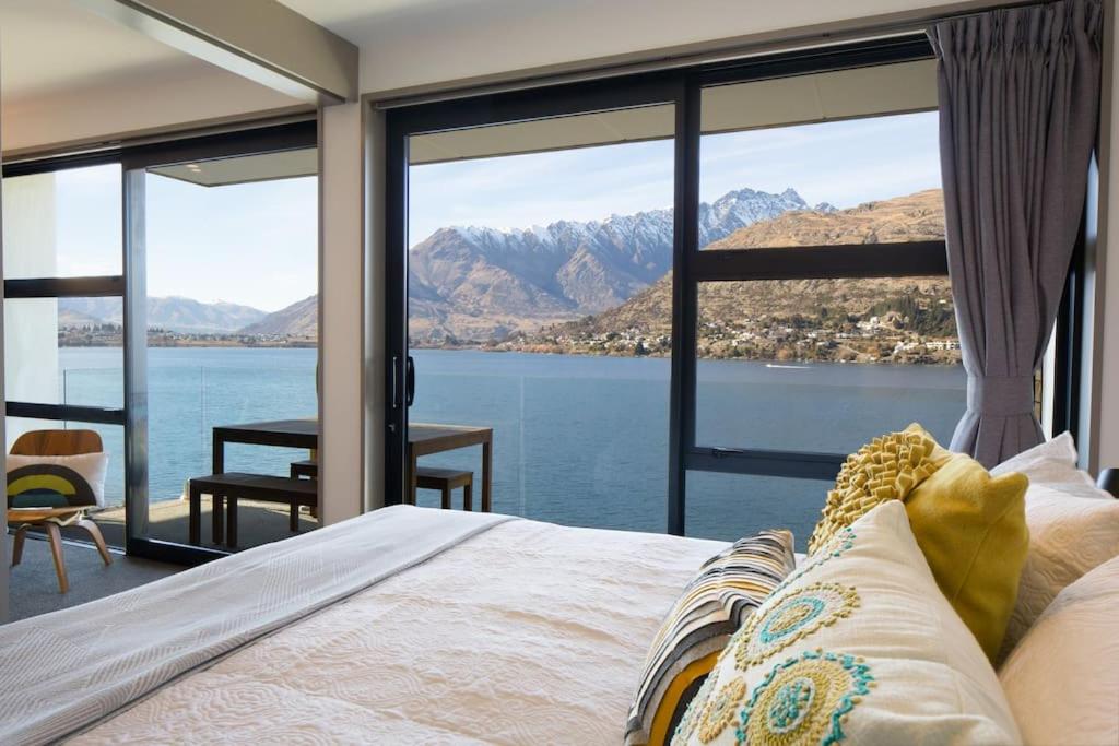 a bedroom with a bed and a view of the water at Hello QT Lakeside Gem in Queenstown