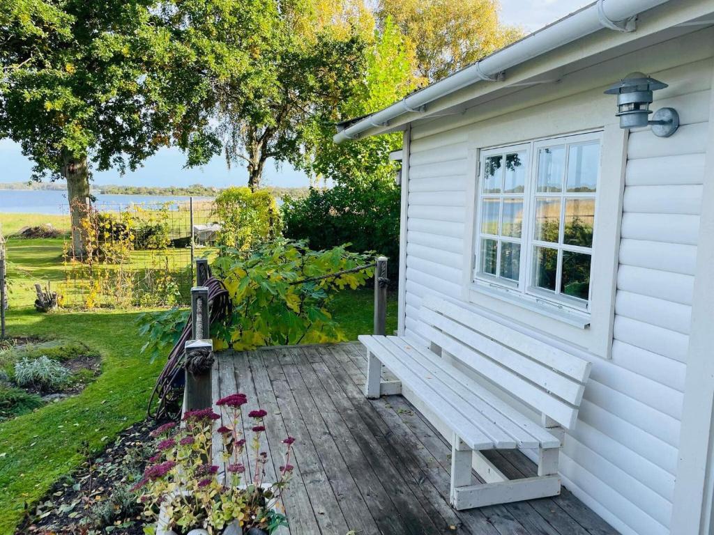 a white house with a bench on a deck at 2 person holiday home in RAMDALA in Trummenas