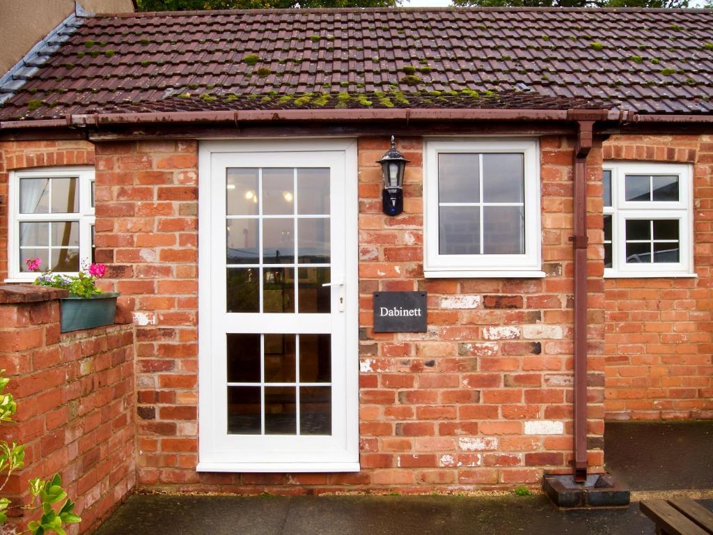 a brick house with white doors and windows at Dabinett in Ledbury