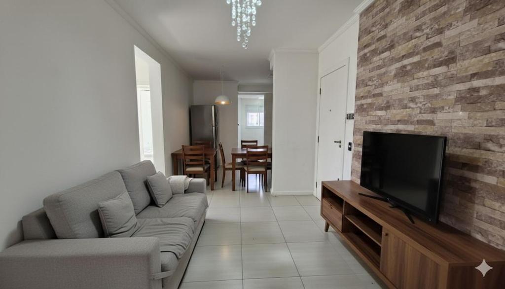 a living room with a couch and a flat screen tv at Apartamento 3 quartos prox passeio Pedra Branca in Palhoça