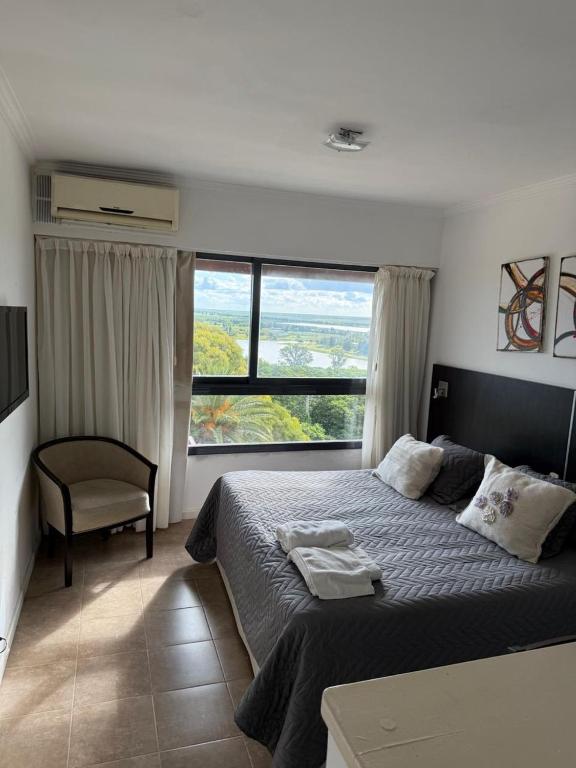 a bedroom with a bed and a chair and a window at Apart -Hotel Rio Manso "Habitación 22" in Victoria