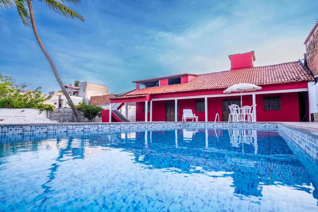 une maison avec une piscine en face d'une maison rouge dans l'établissement Casa a 950 m da Praia de Jauá - Espaçosa e Aconchegante!, à Camaçari