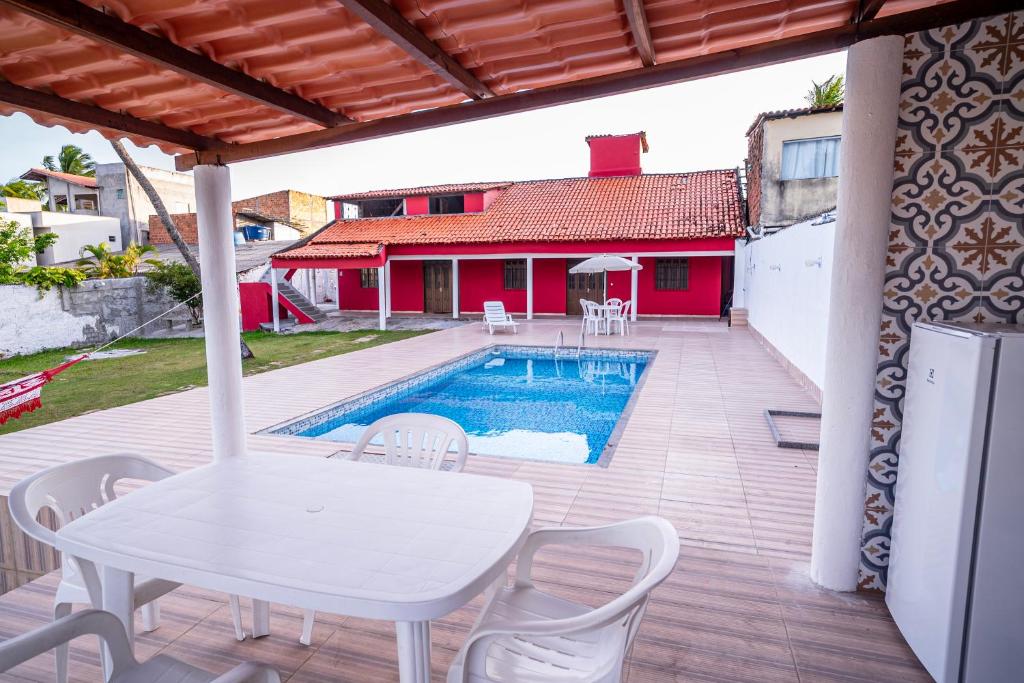 eine Terrasse mit Tisch und Stühlen und einem Pool in der Unterkunft Casa a 950 m da Praia de Jauá - Espaçosa e Aconchegante! in Camaçari